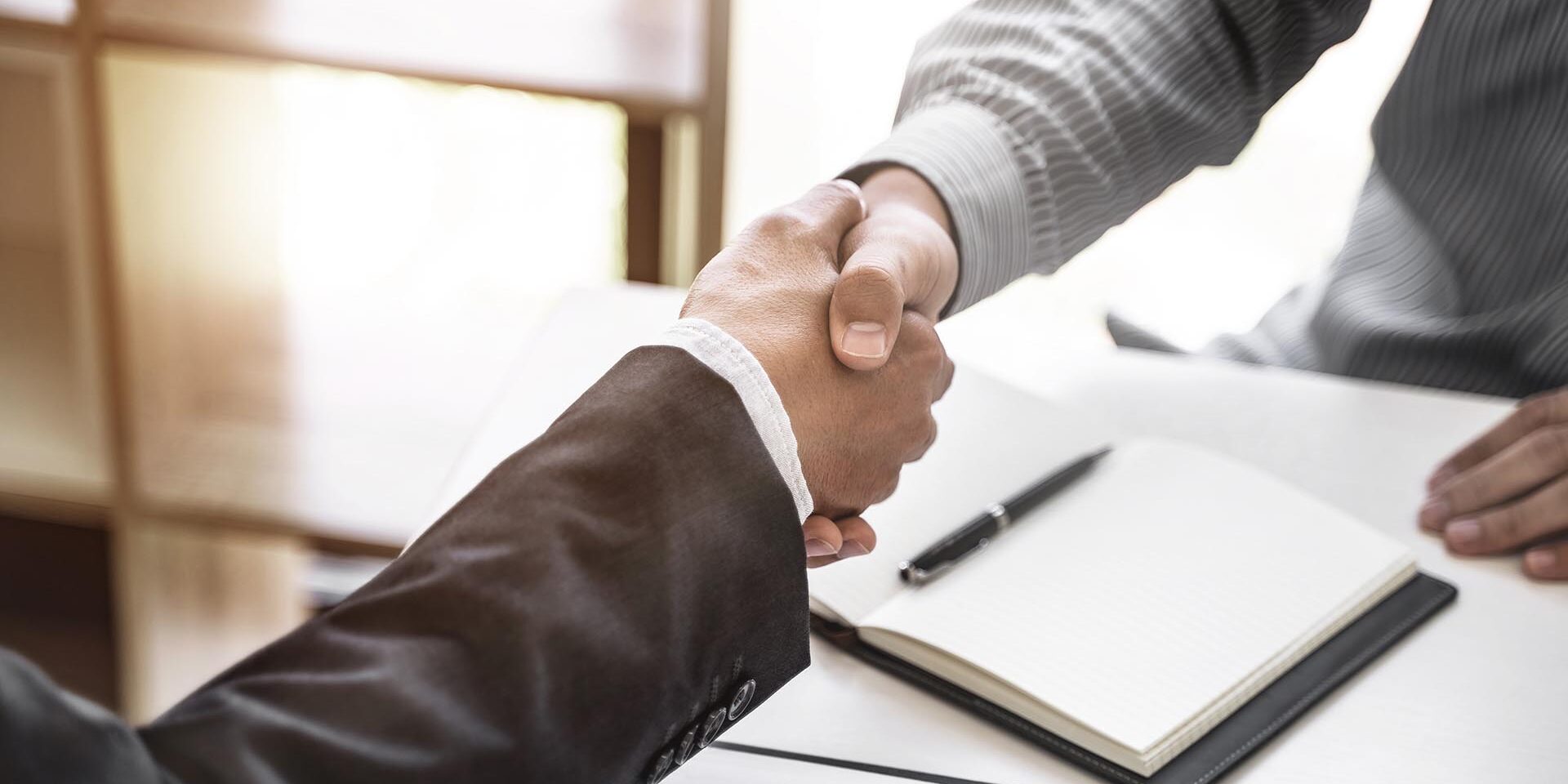 Successful agreement, Justice lawyer hand shaking with Client in Miehet kättelevät ja taustalla näkyy muistivihko sekä kynä