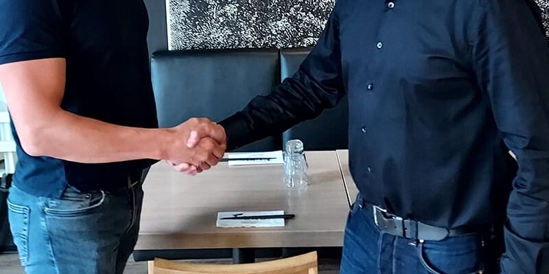 WeGo Groupin asiakkaan Transmerin referenssissä käytetty kansikuva. Kuvassa kaksi miestä kättelevät yhteistyön merkiksi. Taustalla näkyy toimistopöytä.