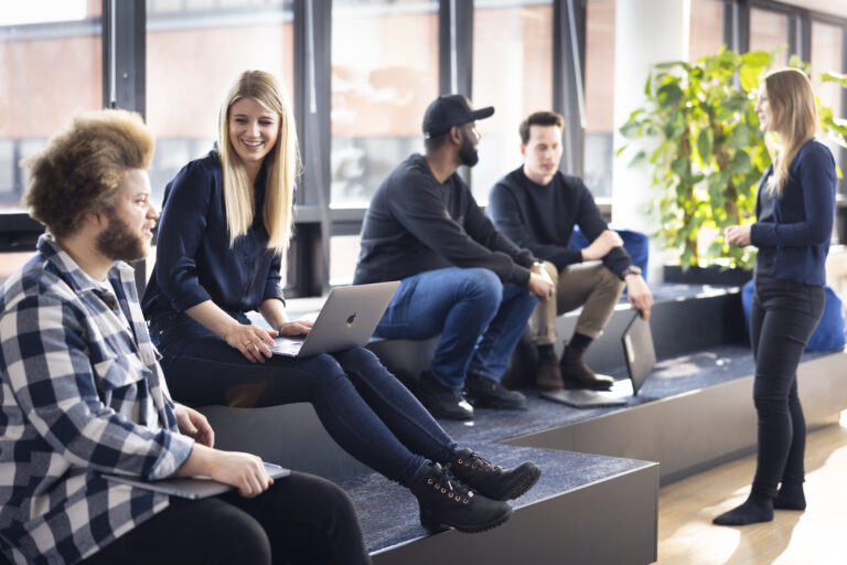 WeGo Groupin asiakkaan Hoxhuntin referenssissä käytetty kansikuva. Kuvassa ihmisiä istuu toimiston portailla tietokoneiden kanssa. Taustalla näkyy viherkasvi.
