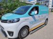 Kuvassa WeGo Groupin asiakkaan Tapiolan Lämmön sähköpakettiauto, jonka kyydissä istuu mies. Auton kyljessä lukee teksti: “Hiilineutraalimpaa kiinteistönhoitoa”.